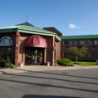 A welcoming hotel entrance with a well-maintained exterior and green roofing.