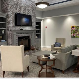 A cozy living room featuring a brick fireplace, wall-mounted television, comfortable seating, and elegant decor.