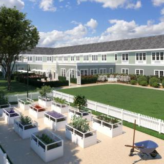 A spacious residential building with a well-maintained garden and outdoor seating area under a clear blue sky.
