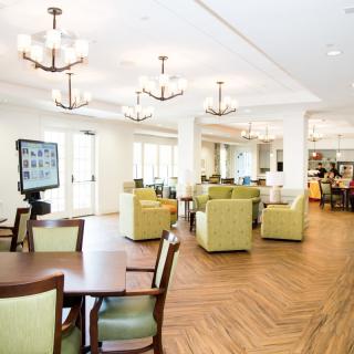 A modern and spacious lounge area featuring comfortable seating, chandeliers, and a well-lit interior.