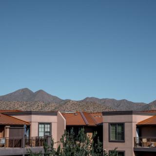 Modern houses with a mountain backdrop under a clear blue sky.