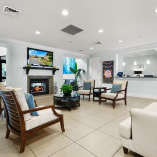 A modern lobby area with comfortable seating, a television, and a fireplace.