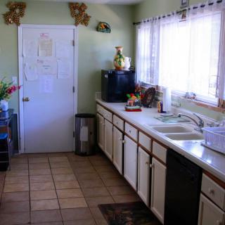A cozy kitchen with tiled flooring, wooden cabinets, and natural light coming through the window.