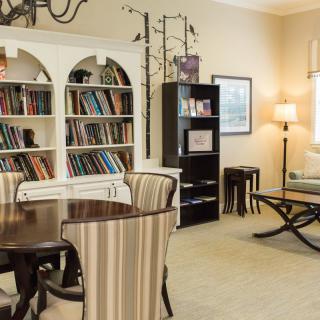 A cozy living room with bookshelves and a table surrounded by chairs.