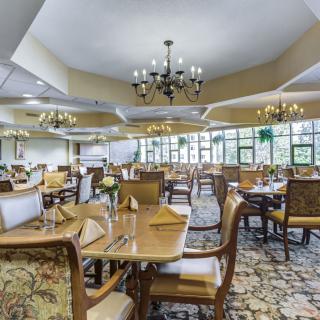 A spacious and elegantly designed dining area with neatly arranged tables, chairs, and decorative chandeliers.