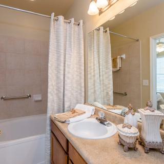 A well-organized bathroom with a sink, mirror, and shower curtain.