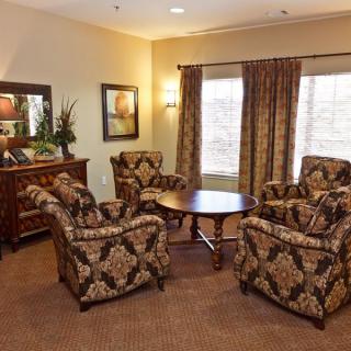 A cozy living room with patterned chairs, a round wooden table, and elegant decor.
