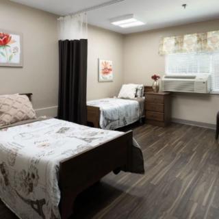 A cozy bedroom with two neatly made beds, decorated with floral art and soft lighting.