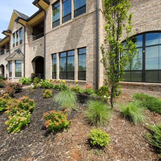A well-landscaped exterior of a modern brick building with large windows.