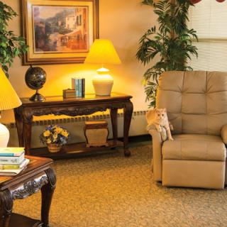 Cozy living room with an armchair, table, lamp, and decorative elements.