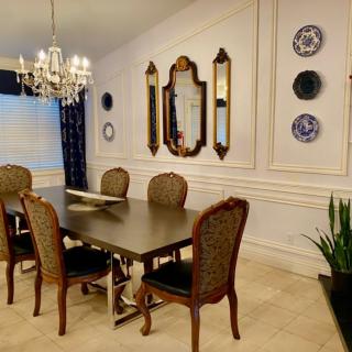 An elegant dining room featuring a classic chandelier, ornate mirrors, and sophisticated wall decor.