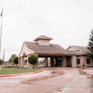 A building with a covered entrance and driveway on a cloudy day.