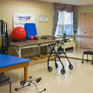 A physical therapy room equipped with various rehabilitation tools such as a walker, parallel bars, and exercise balls.