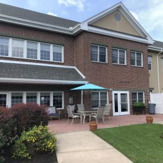 A two-story brick building with outdoor seating and a blue umbrella on the patio.