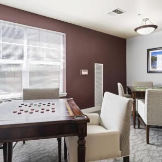 A cozy interior space featuring a game table and comfortable seating with natural light streaming through a window.