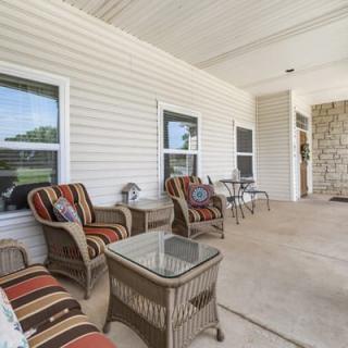 A cozy porch area with wicker furniture and striped cushions provides a relaxing outdoor space.