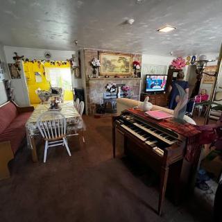 A cozy living room featuring a piano, table with chairs, and a television.