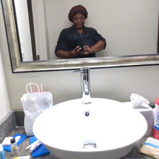 A person taking a selfie in a bathroom mirror surrounded by various toiletries.
