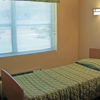 A simple bedroom with a single bed and window blinds.