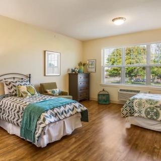 A cozy bedroom with twin beds and ample natural light streaming through a large window.