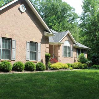 A brick house with a well-maintained front yard and shrubs.