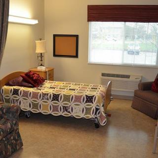 A simple hospital room with a single bed, lamp, and window.