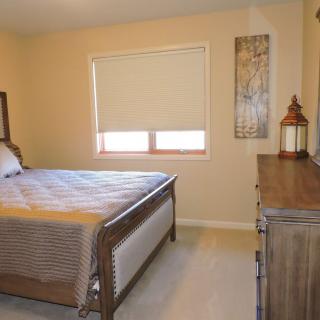 A cozy bedroom with a bed, dresser, and window providing natural light.