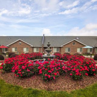 A beautiful garden featuring vibrant flowers and a decorative fountain in front of residential buildings.