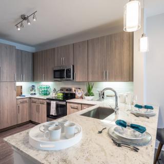 A modern kitchen interior featuring wooden cabinets and a sleek countertop with dining setup.