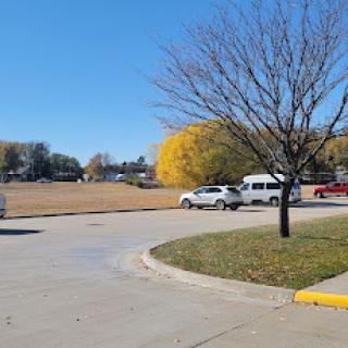 A sunny day at the park with a clear blue sky and colorful autumn trees.