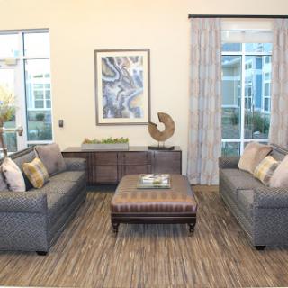 A cozy and modern living room setup featuring gray sofas, a stylish coffee table, and large windows allowing natural light to fill the space.