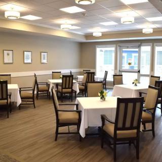 An empty dining room with neatly arranged tables and chairs, illuminated by overhead lights.