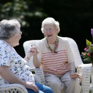 Two elderly women enjoying a conversation outdoors.