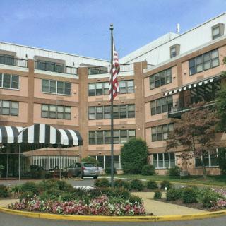 A well-maintained hotel featuring a flagpole and colorful flower beds in the foreground.