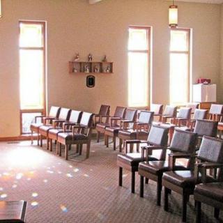 A serene chapel interior with rows of chairs and natural lighting.