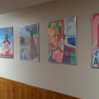 A hallway featuring a series of colorful paintings displayed on the wall.
