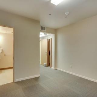 An empty interior room with beige walls and a connecting hallway.