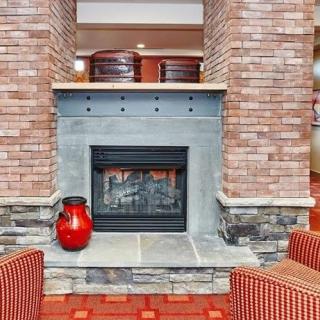 A cozy lounge area featuring a brick fireplace and a decorative red vase.