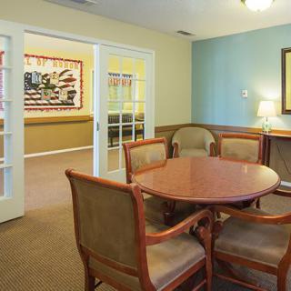 A cozy dining area with a wooden table and chairs, featuring wall artwork and soft lighting.