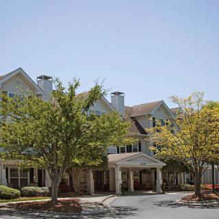 A multi-story residential building surrounded by trees under a clear sky.