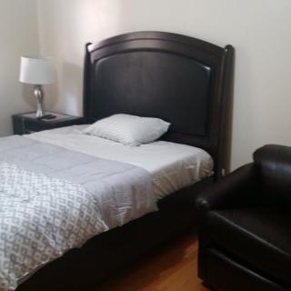 A cozy bedroom with a single bed, bedside lamp, and armchair.