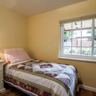 A cozy bedroom with a single bed and a colorful quilt by the window.