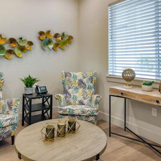 A cozy living room with floral chairs, a round wooden coffee table, and decorative wall art.