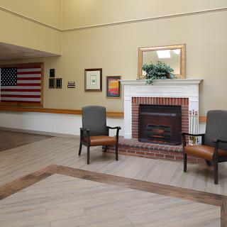 A lobby area featuring a brick fireplace, two chairs, and an American flag on the wall.