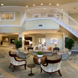 A spacious and elegantly designed lobby area with comfortable seating, indoor plants, and a staircase leading to the upper level.