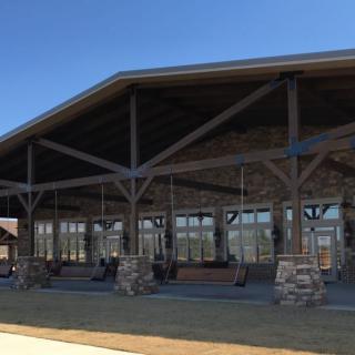 A spacious pavilion with stone columns and a wooden roof structure under a clear blue sky.