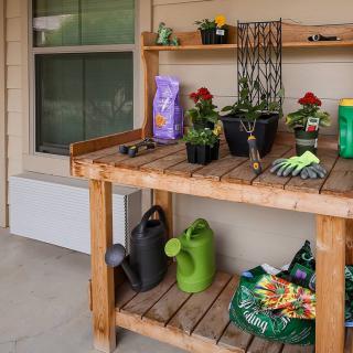 An outdoor potting bench with gardening supplies and potted plants.