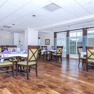 A bright and spacious dining area with wooden floors and neatly arranged tables and chairs.
