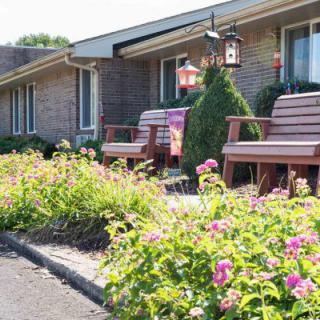 A cozy brick house with a beautifully landscaped garden featuring flowers and outdoor seating.