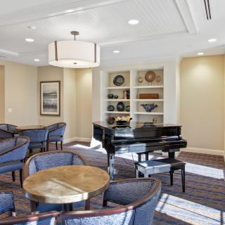 A well-lit lounge with a grand piano and comfortable seating areas.